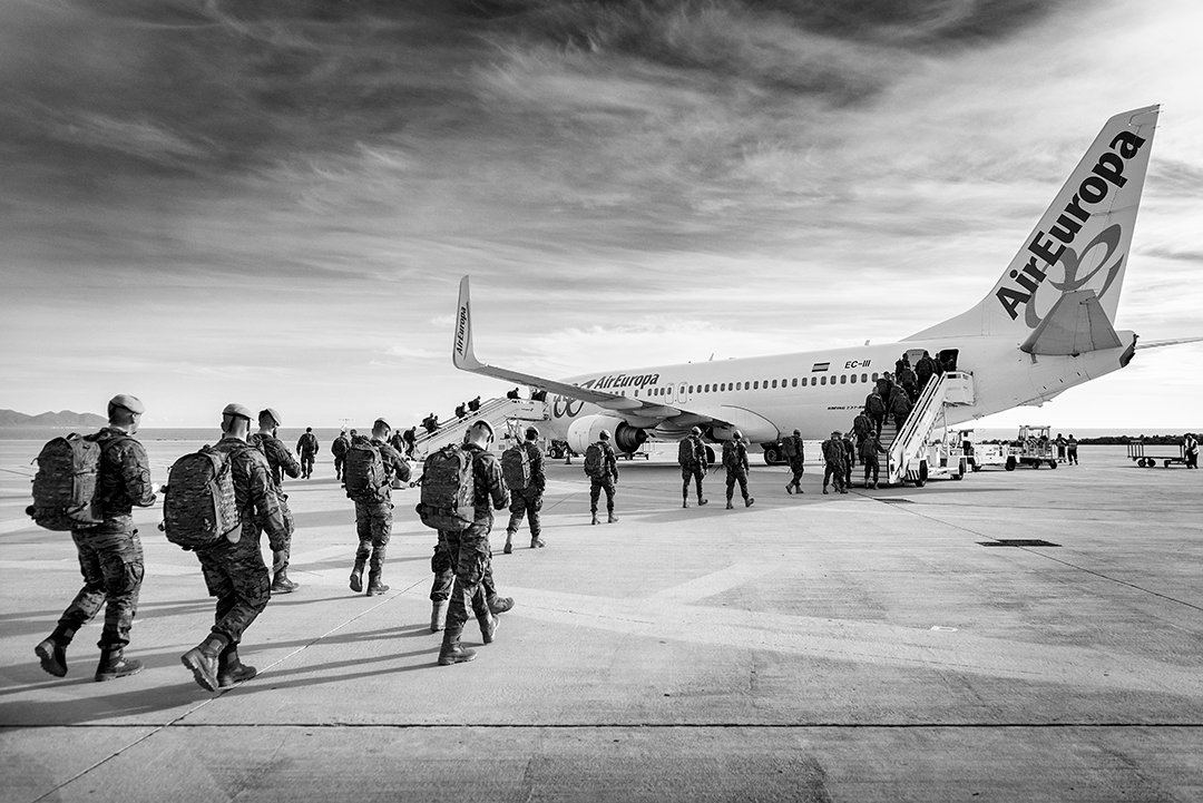 Service members walking towards an aircraft on a runway.